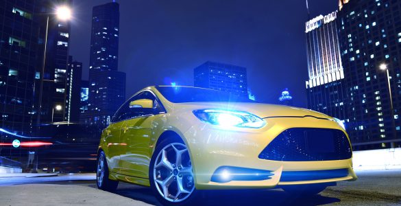 Beleuchtetes gelbes Auto mit Xenonscheinwerfer in einer Großstadt